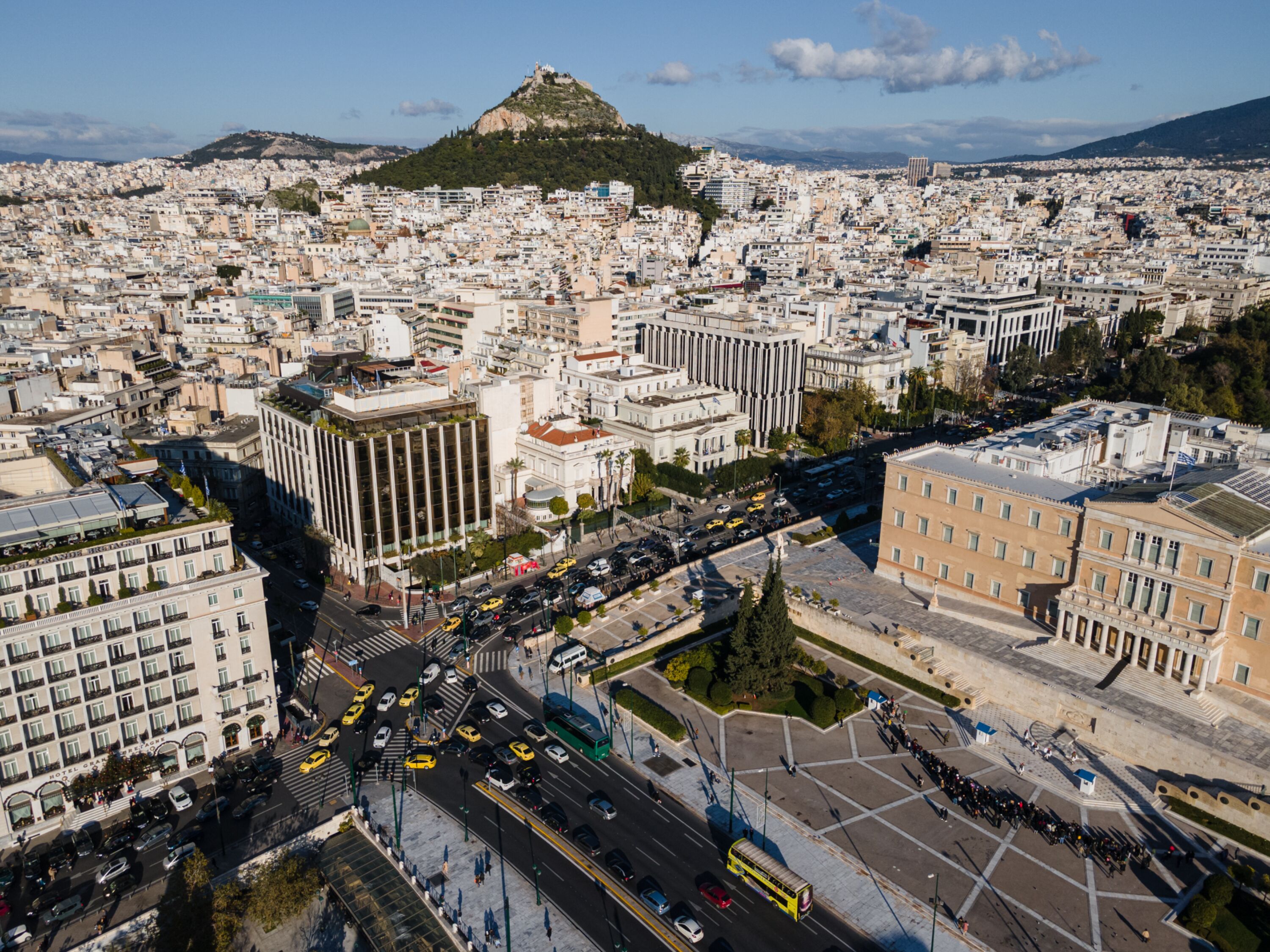 A cityscape with a prominent hill in the background, featuring a mix of modern and historical architecture.