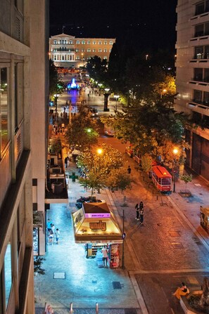 Une vue nocturne d’une place de ville avec une fontaine, des lampadaires et un tramway.