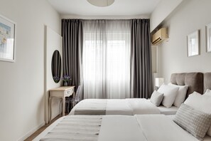 A hotel room with two beds, a desk, a chair, a mirror, and a window with curtains. - Syntagma Spotlight Residence (Athens)