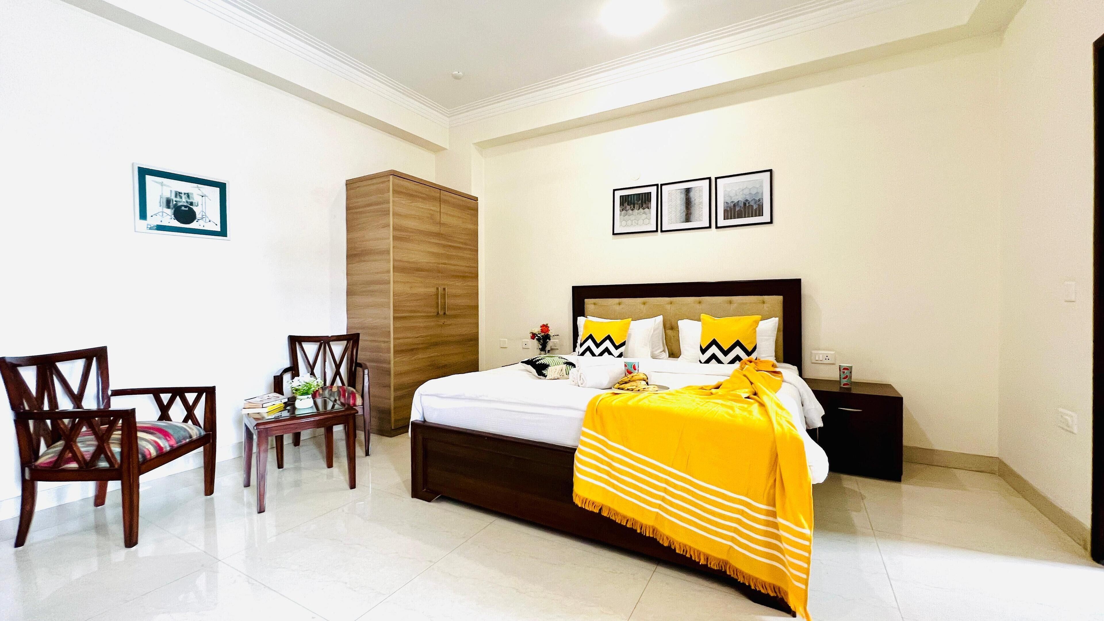 Un dormitorio ordenado con una cama, una silla, un armario y una mesita.