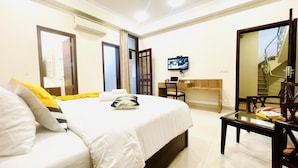 A hotel room with a bed, a desk, a chair, a TV, and a mirror. - Olive Service Apartment-Golf Course Road (Gurugram)