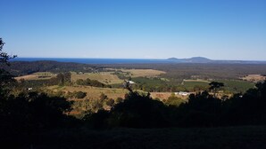 Ein weiter Panoramablick auf eine ländliche Landschaft mit sanften Hügeln, einem entfernten Berg und blauem Himmel.
