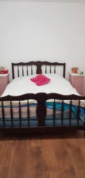 Een bed met houten frame en witte beddengoed.