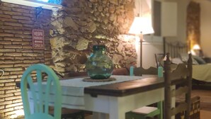 Un comedor con pared de piedra, un letrero de estacionamiento para Vespa, un jarrón verde y una mesa con sillas.