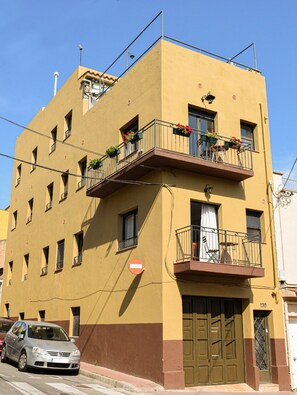 Un edificio de varios pisos con balcones, un coche estacionado adelante y el número 130 visible.
