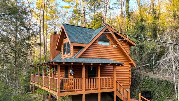 Una baita di legno con un balcone, immersa nel verde.