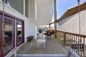 Une terrasse en bois dotée d’un espace couvert, de mobilier d’extérieur et d’un barbecue.