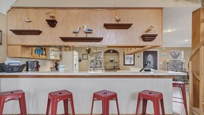 Una cocina con barra de madera, taburetes rojos y adornos de gaviotas.
