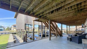 Un espacio al aire libre cubierto con una terraza de madera, mobiliario exterior y vistas del barrio circundante.