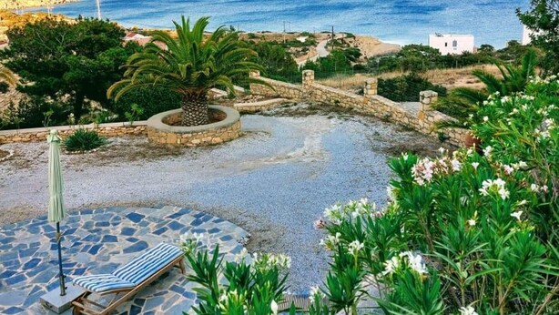 Un jardin en bord de mer avec un sentier en pierre, un fauteuil de relaxation et une vue sur la mer.