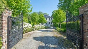 A cobblestone pathway leading to a gated entrance with a brick wall and metal gate. - Le Château des Comtesses (Montignies-sur-Roc)