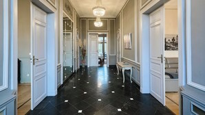A hallway with black and white tiled flooring, white doors, and a chandelier. - Le Château des Comtesses (Montignies-sur-Roc)
