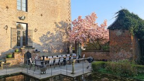 A courtyard with a brick building, outdoor seating, and a water feature. - Le Château des Comtesses (Montignies-sur-Roc)