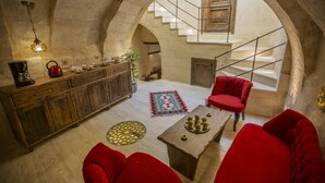 Un intérieur chaleureux avec un meuble en bois, un canapé rouge, une table basse et un escalier menant à un niveau supérieur.