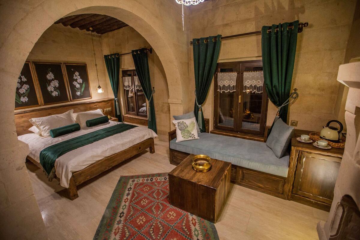 Um quarto aconchegante com uma cama de madeira, um sofá-cama e uma pequena mesa com uma chaleira.