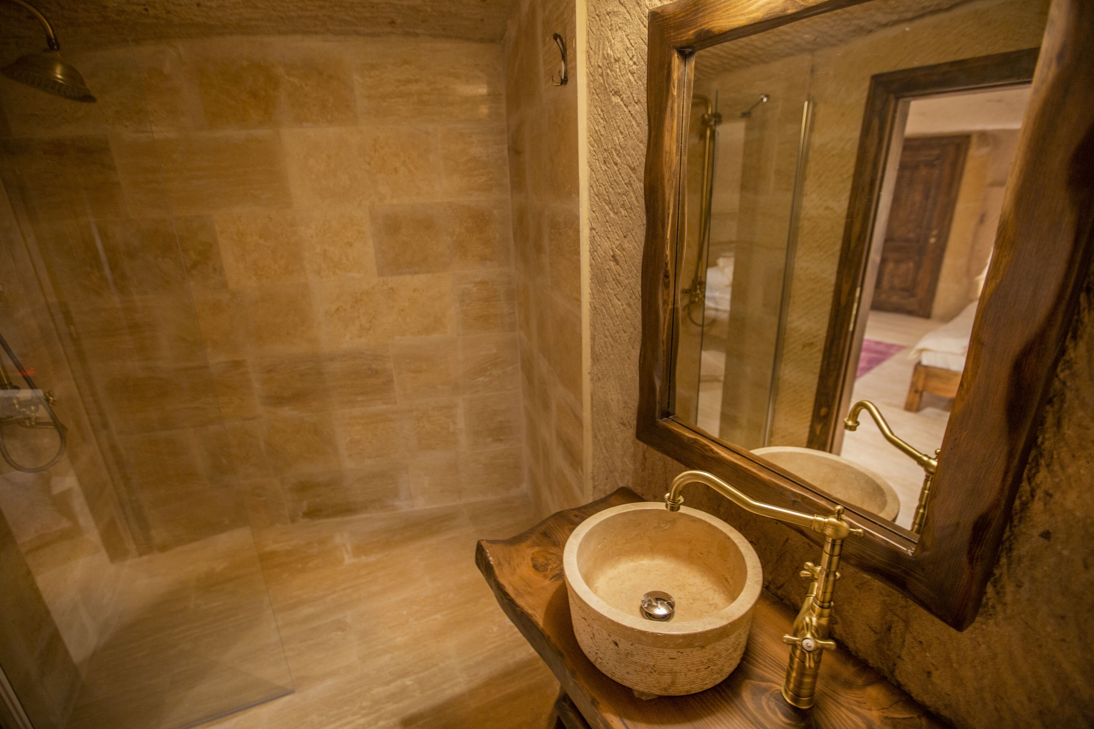 A bathroom with a stone wall, a wooden vanity, a round sink, and a mirror.