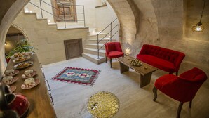 Un vaste espace de vie agrémenté d’une haute porte en arc, d’un canapé rouge, d’une table basse en bois et d’un tapis à motifs.
