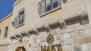 A building with a stone facade, a wooden door, and a sign that reads "MAK'S". - Mak's Cave House (Nevsehir)