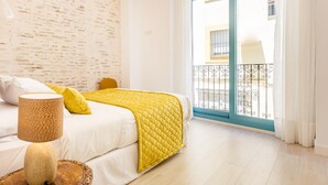 A bedroom with a bed, a lamp, and a view of a balcony.