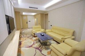 Una habitación de hotel con un conjunto de sofá, una mesa de centro y un televisor de pantalla plana.
