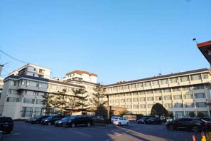 A multi-story building with a parking lot in front. - Nanxiong Guest House (Nanxiong)