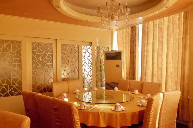 A dining area with a round table, chairs, and a chandelier.