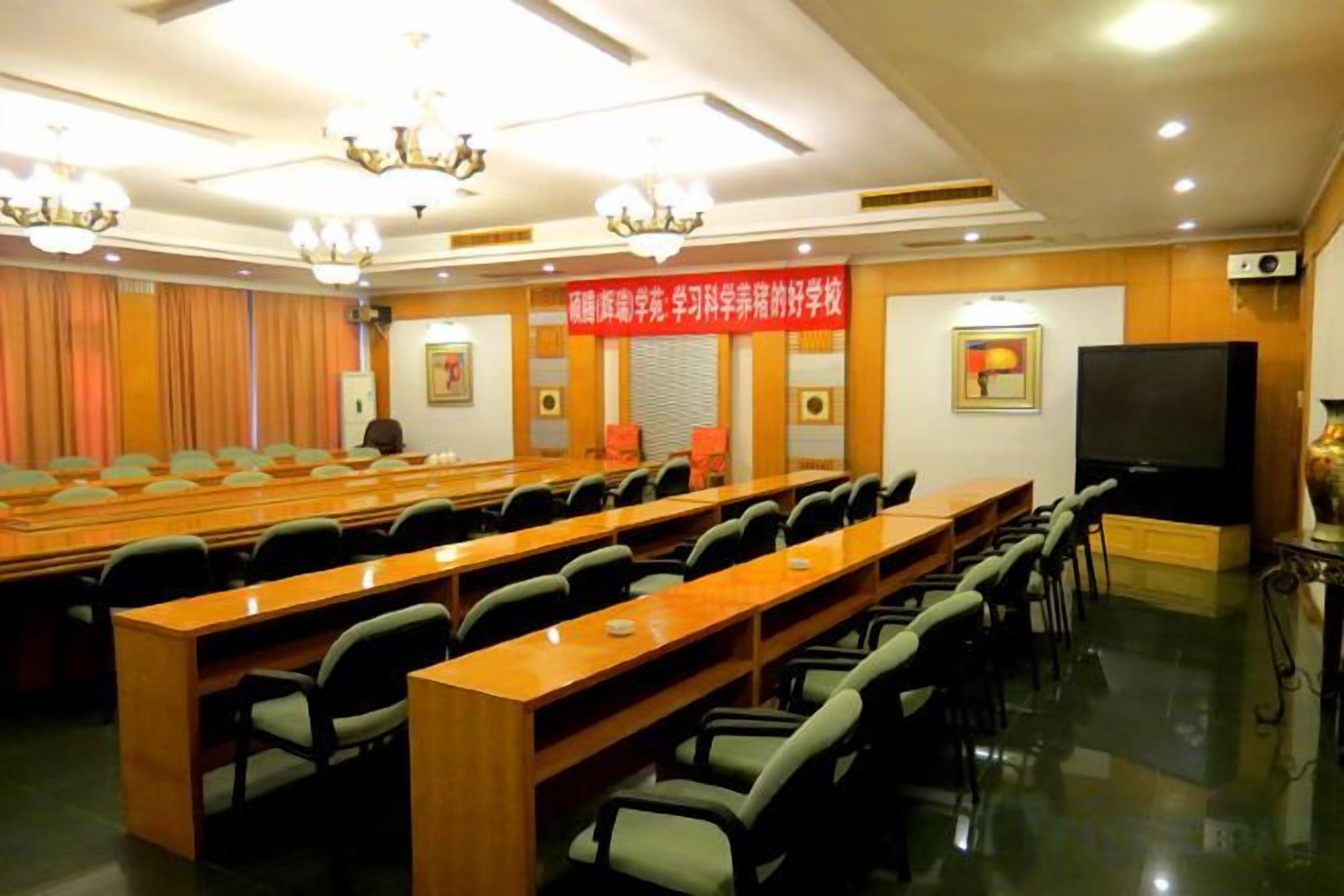 A conference room with a long table, multiple chairs, a television, and a banner on the wall.