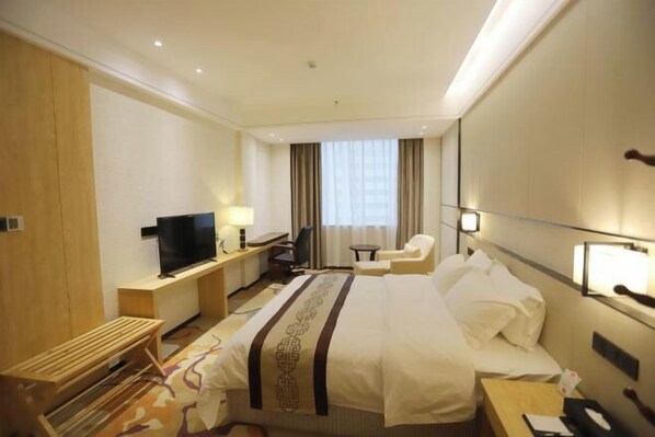 Une chambre d’hôtel équipée d’un lit, d’une télévision, d’un bureau, d’une chaise et d’une fenêtre avec des rideaux.