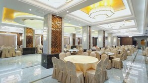 Une salle de banquet spacieuse, dotée de tables rondes, de hauts plafonds et de lustres modernes.