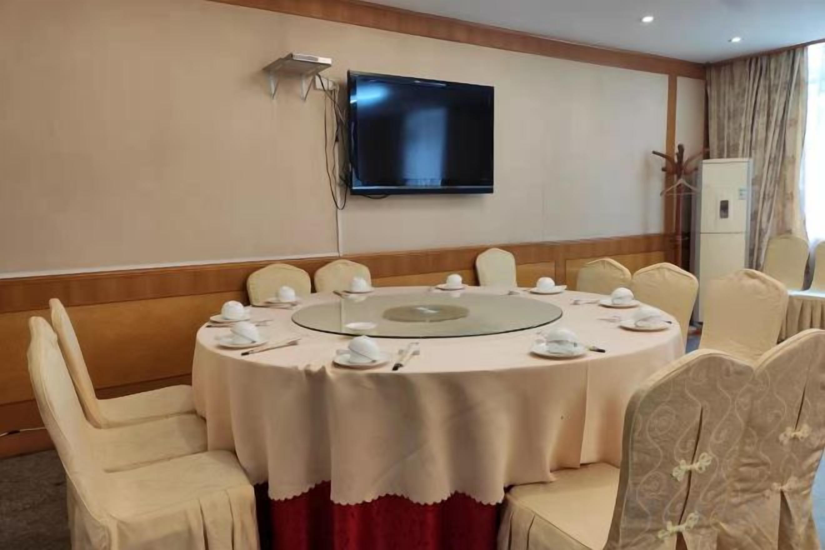 A conference room with a round table, chairs, and a television mounted on the wall.
