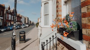 A street view with a row of terraced houses, a sidewalk, and a parked car.