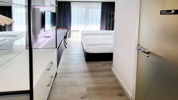 Een hotelkamer met een bed, een bureau met stoel, een klein tafeltje en een kledingkast.