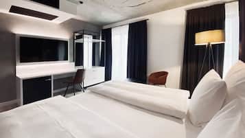 Een hotelkamer met twee bedden, een bureau, een stoel, een televisie en een lamp.