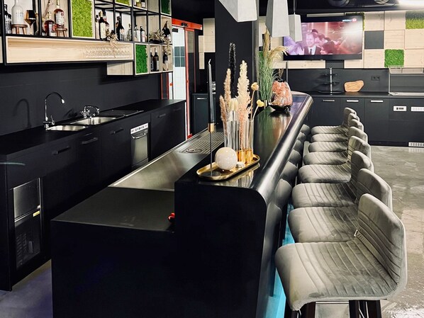 Una cocina moderna con una isla grande, electrodomésticos integrados y un televisor de pantalla plana en la pared.