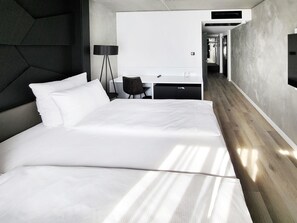Una habitación de hotel moderna con una cama grande, un escritorio y una silla.