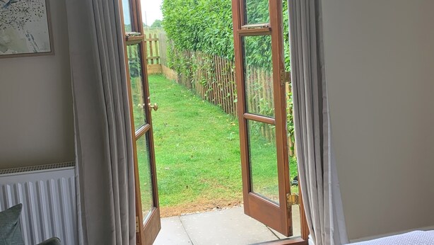 A bedroom with a large window, a bed, a chair, and a radiator. - Come & Stay on a Real Norfolk Vineyard (Norwich)