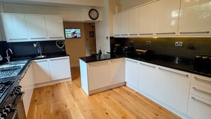 A modern kitchen with white cabinets, a wooden floor, and a central island. - Park View (Scarborough)