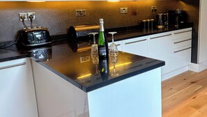 A modern kitchen with white cabinets, a black countertop, and a built-in toaster. - Park View (Scarborough)