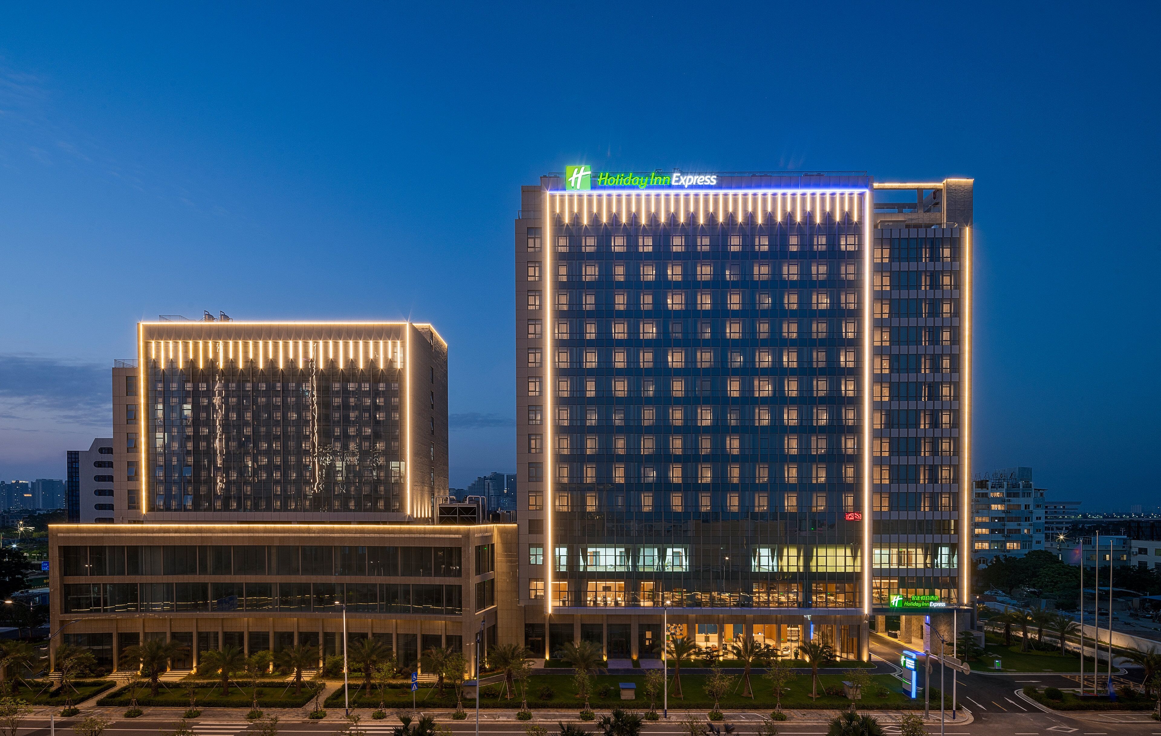 Un hotel Holiday Inn Express con fachada moderna, ventanas amplias y un letrero llamativo.