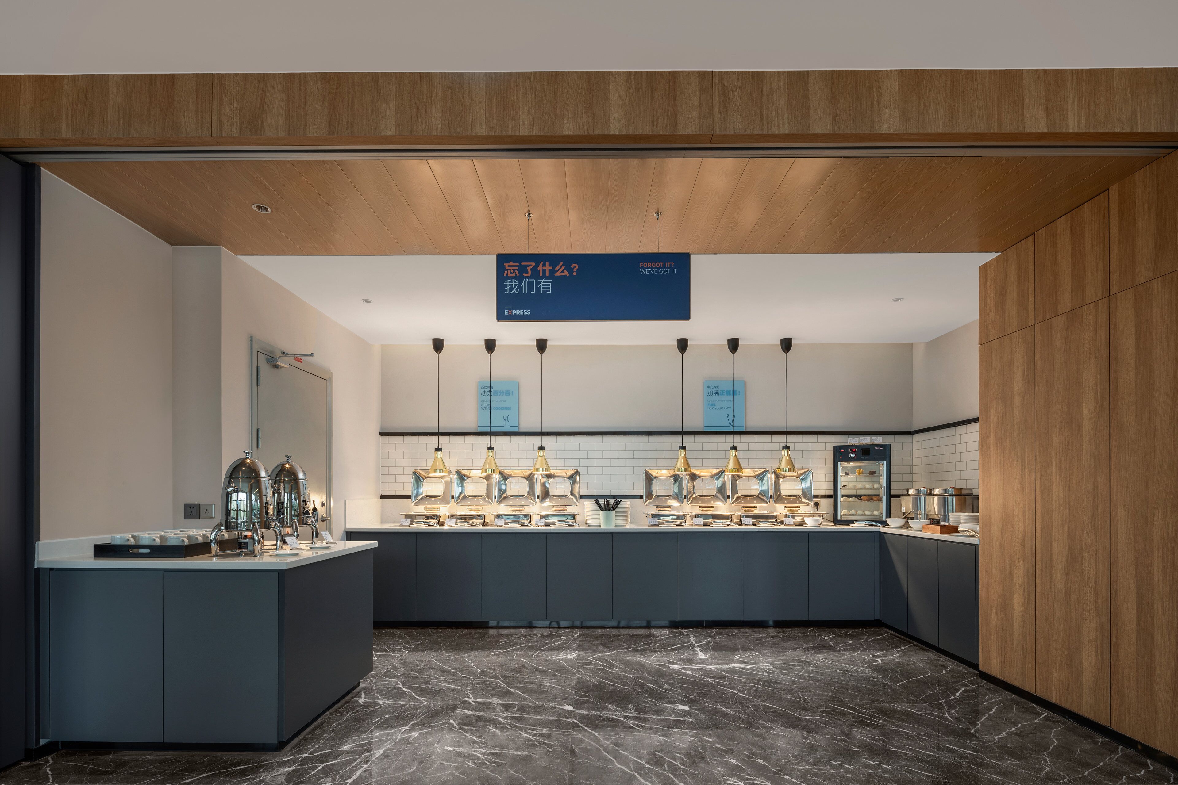 Una cocina moderna con piso de mármol, armarios de madera e iluminación colgante.