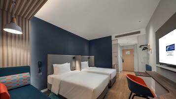 A hotel room with two beds, a desk, a chair, and a TV.