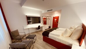Una habitación de hotel moderna con una cama grande, un escritorio y una silla.