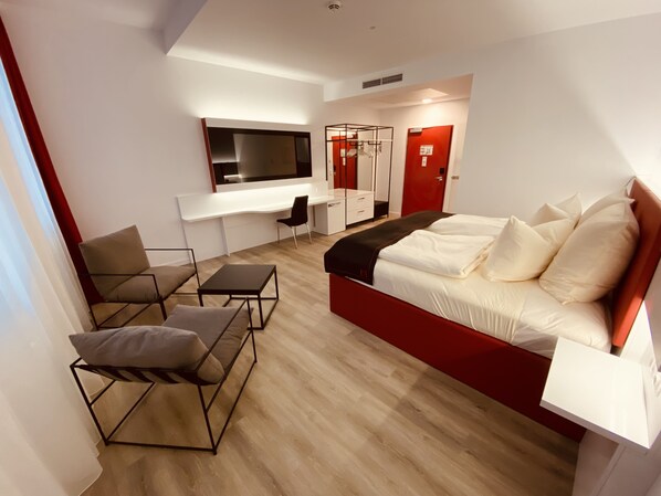 Una habitación de hotel moderna con una cama grande, un escritorio y una silla.