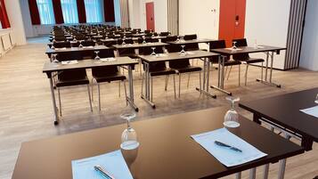 A conference room with rows of tables, each with a pen and a glass of water.