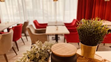 A modern dining area with red and beige chairs, a wooden table, and a potted plant.