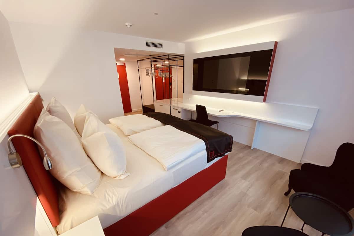 Une chambre moderne avec un grand lit, un bureau et une télévision.