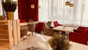 Un interior de restaurante con mesas, sillas y una planta decorativa sobre una mesa.