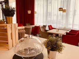 Un interior de restaurante con mesas, sillas y una planta decorativa sobre una mesa.