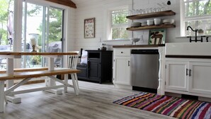A kitchen with white cabinets, a wooden bench, and a colorful rug.