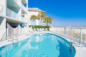 Relax by the pool surrounded by palm trees and lounge chairs.